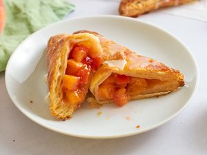 Peachfilled turnover pastry cut open on a white plate