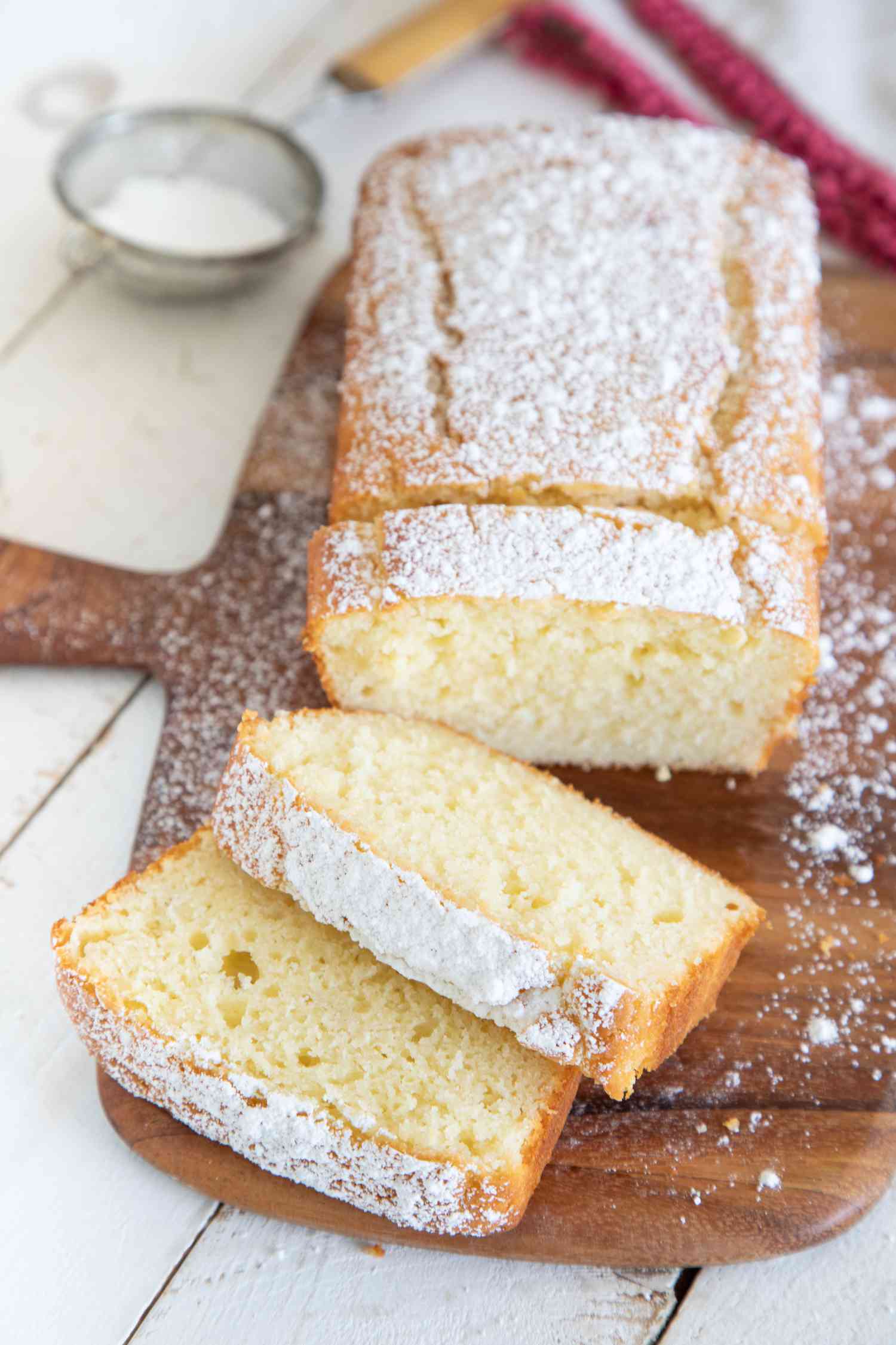 Easy Yogurt Cake on a wooden paddle with a few slices cut.