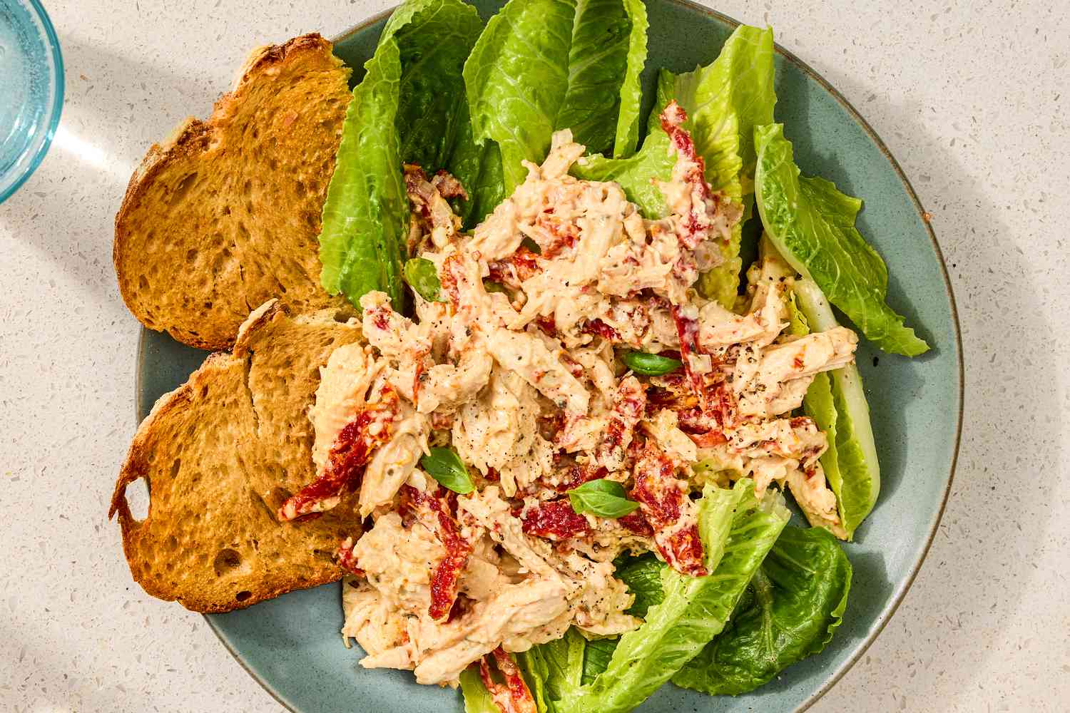 Chicken salad served on a bed of lettuce with slices of toasted bread on a plate