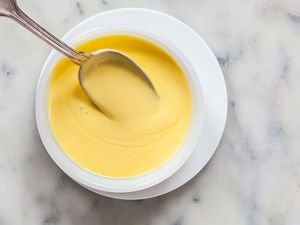 Classic Hollandaise Sauce in a small bowl with a spoon.