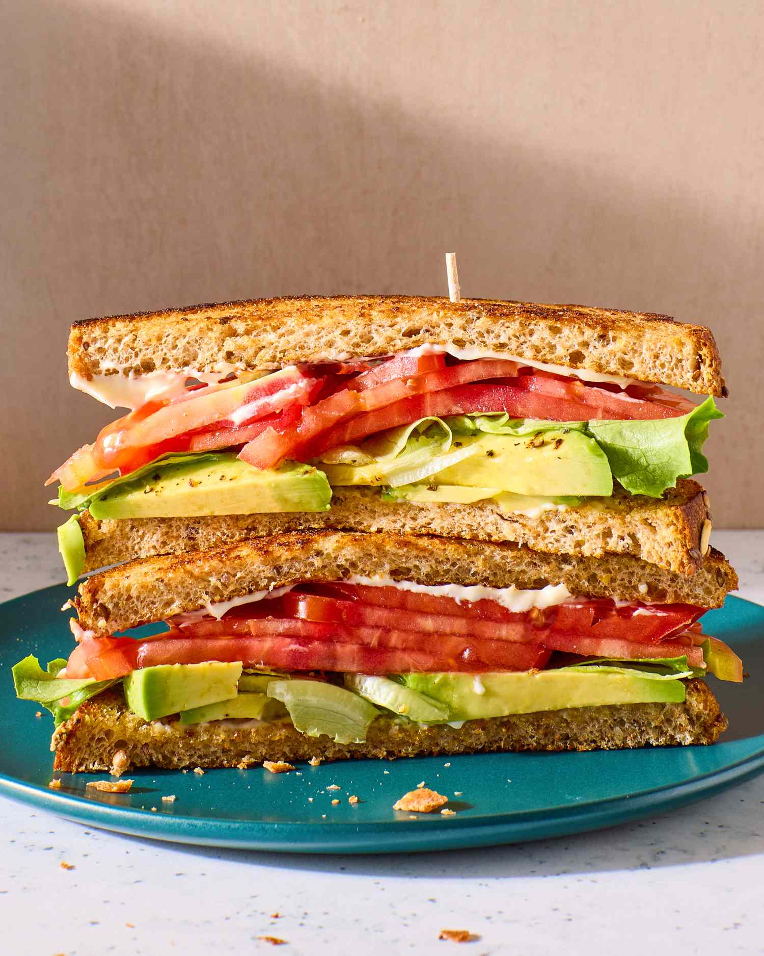 A sandwich of sliced tomatoes, avocado, butter lettuce, and mayonnaise on toasted whole-wheat bread
