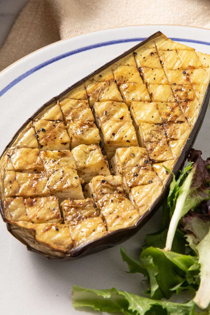 Roasted Eggplant Half on a Plate With a Side Salad