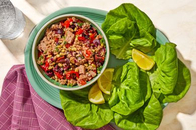 Overhead view of a bowl of italian-style tuna salad on a plate with lemon slices and lettuce