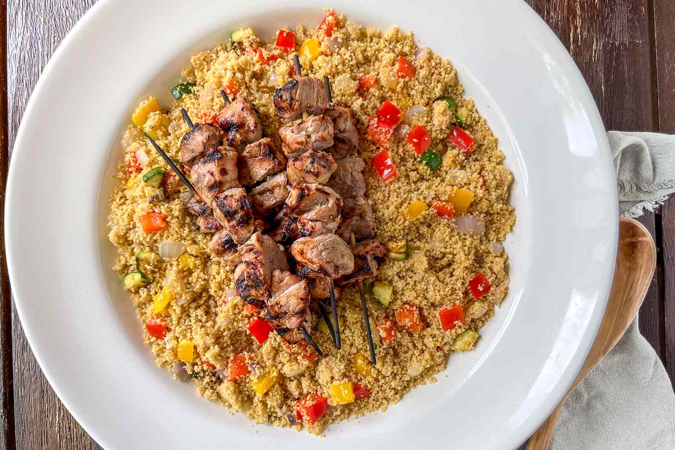 bowl of grilled pork over summer veggie couscous