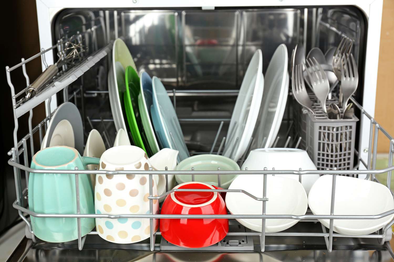 Open dishwasher filled with various dishes and utensils