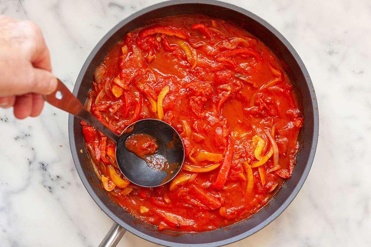 A ladle in a skillet to make Easy Shakshuka.