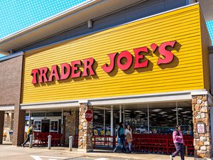 Exterior view of a Trader Joe's store entrance with patrons entering and exiting