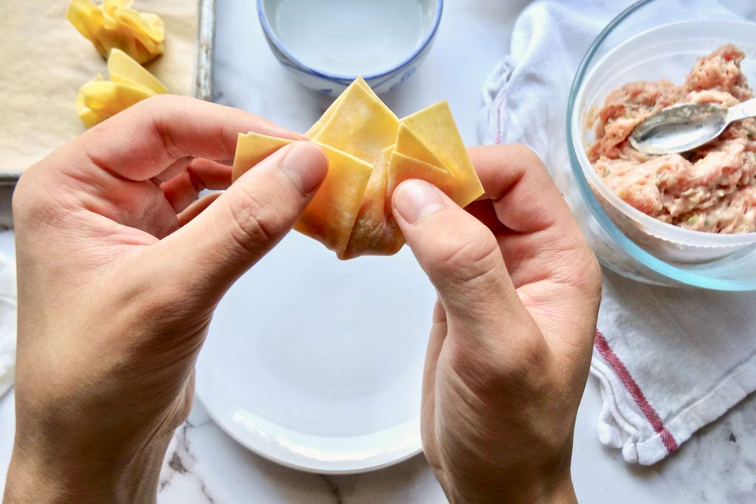 Folding wonton edges to make pork and ginger wontons in chicken soup