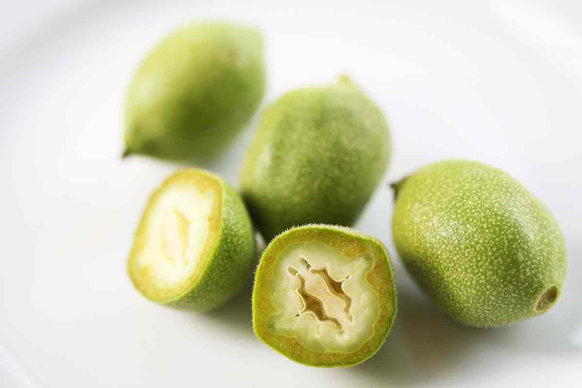 green walnuts on a plate, one cut open