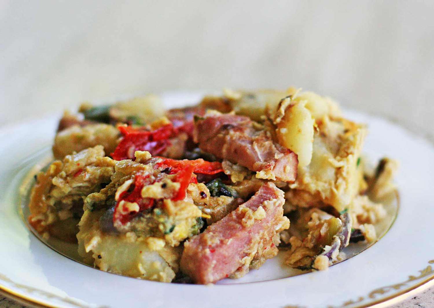 German breakfast of ham, potatoes and bell pepper on a white plate