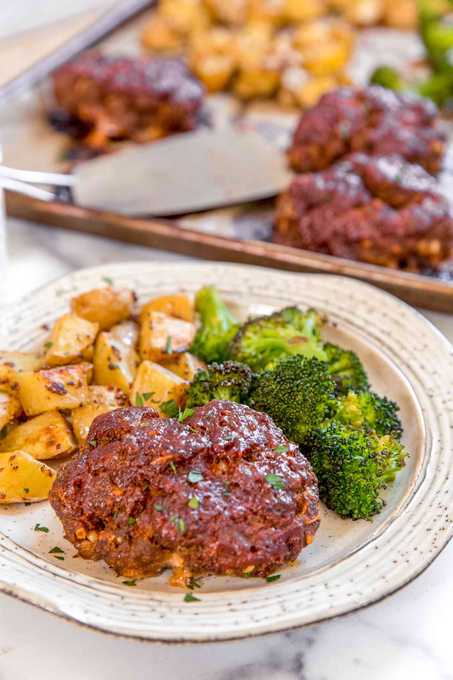 Sheet pan meatloaf dinner on a plate with broccoli and potatoes.