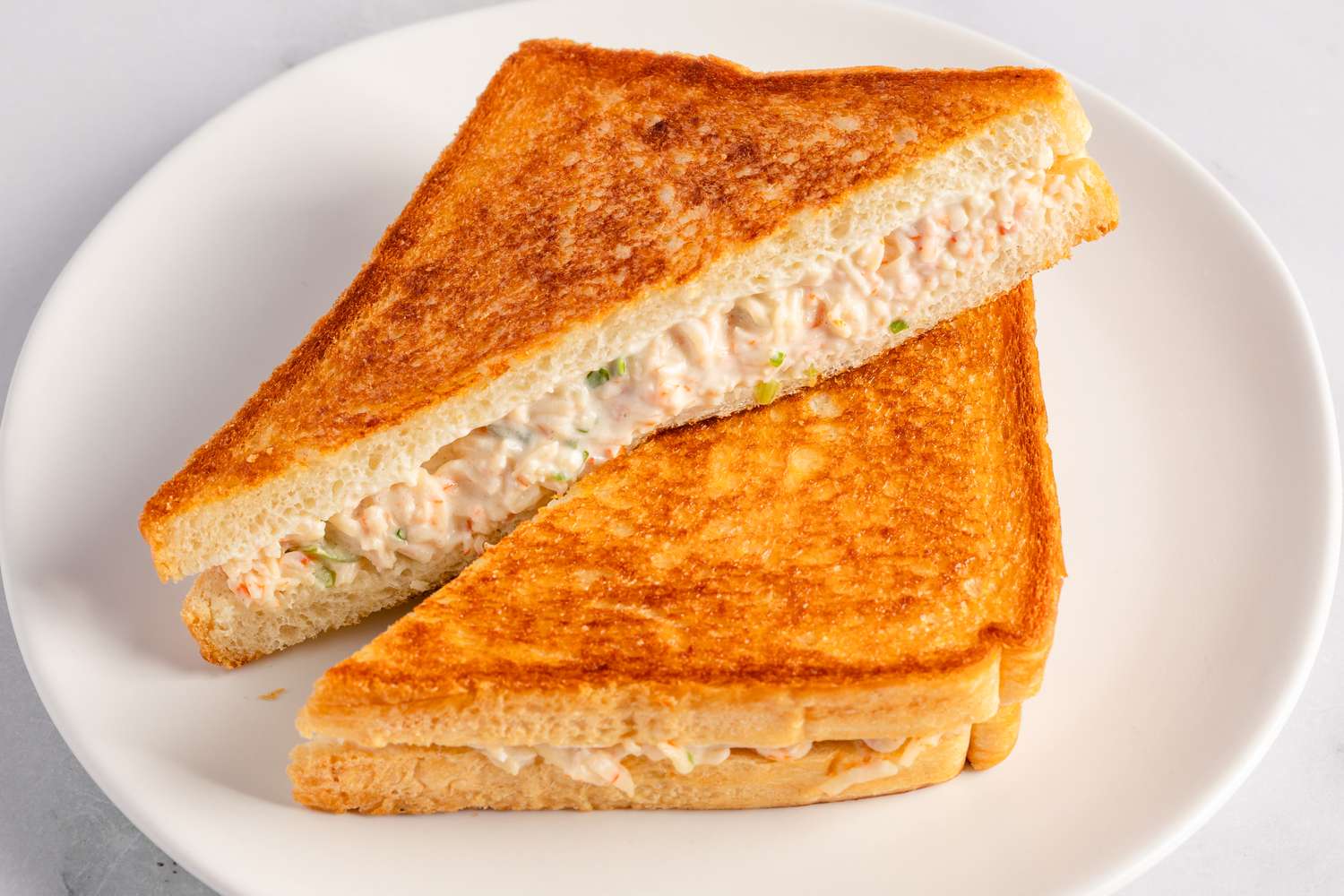 A crab rangoon sandwich sliced in half on a white plate