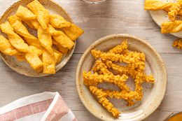Multiple Plates with Cheese Straws (One with Twisted Cheese Straw, Another with Piped Cheese Straws, and the Last with a Mixture) Next to a Kitchen Towel 