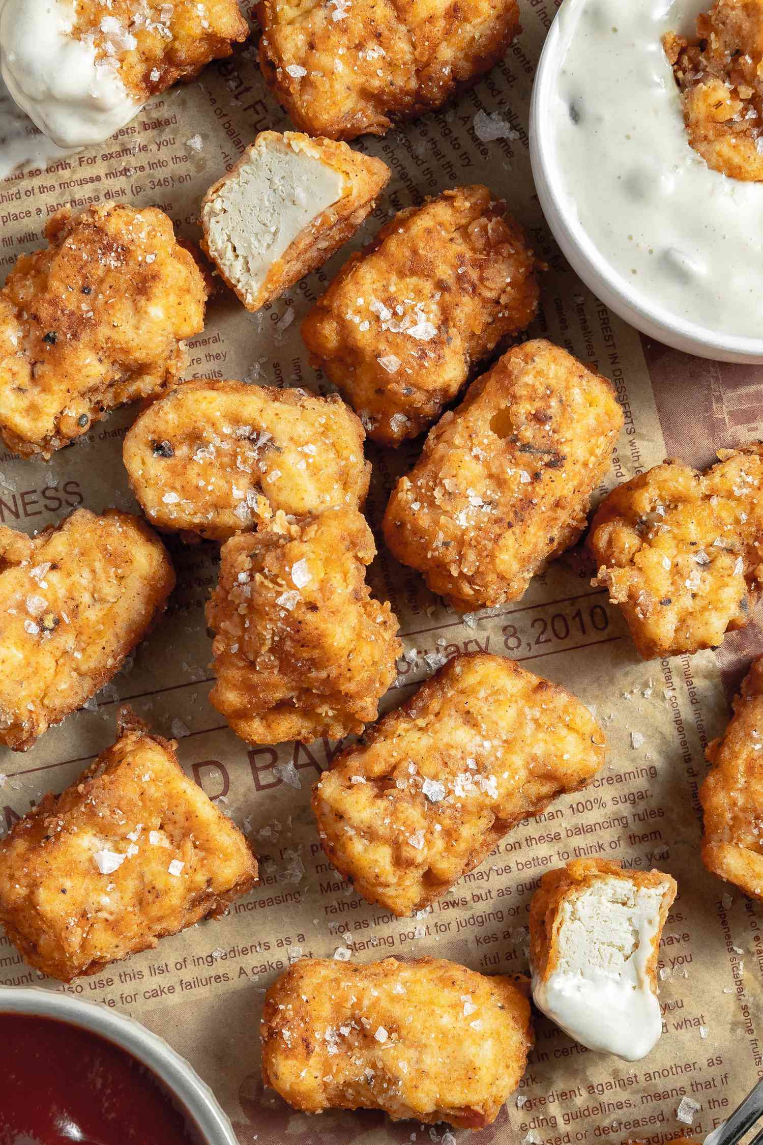 Vegan Chicken Nuggets Sprinkled with Salt Flakes on a Newspaper with Two Bowls of Sauces 