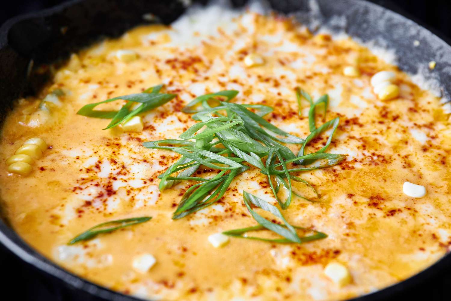 Close-up: Korean Corn Cheese Topped With Sliced Green Onions in a Cast Iron Skillet