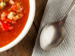 A bowl of soup next to a spoon on a striped napkin