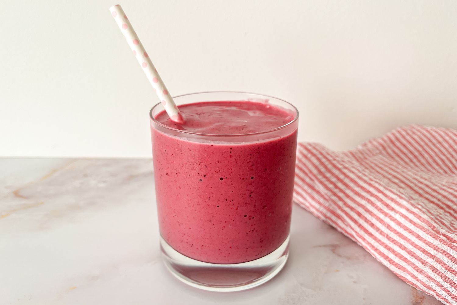 3-ingredient smoothie in a short glass with a white paper straw with light pink polka dots