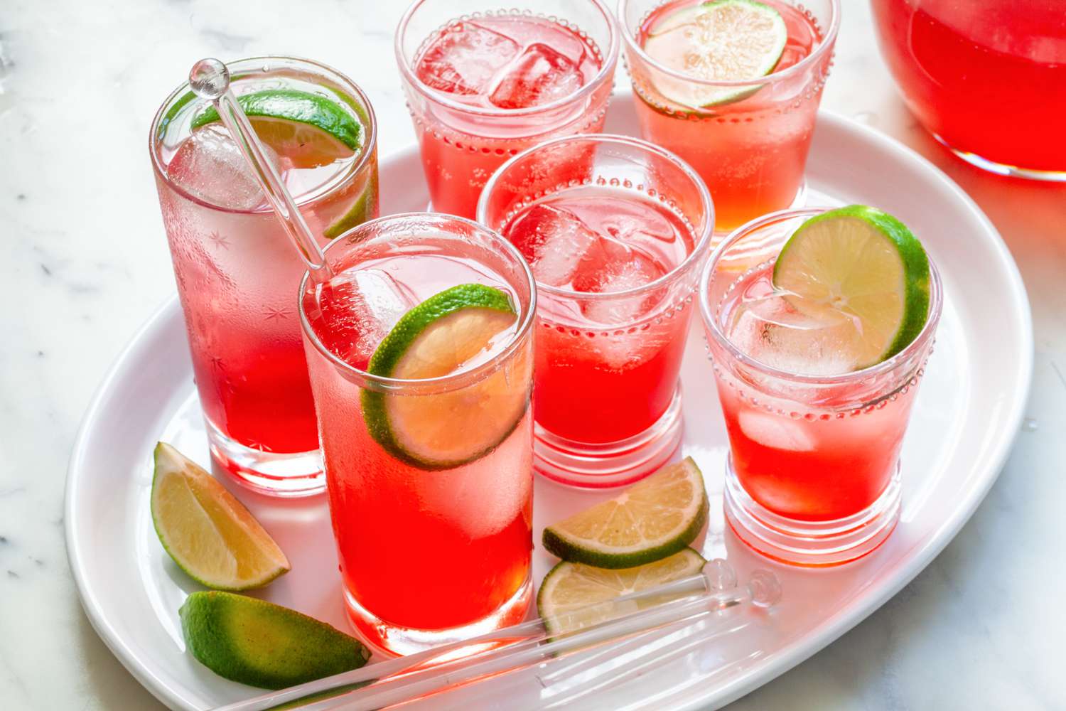 Highball glasses of raspberry lime rickey set on a tray.