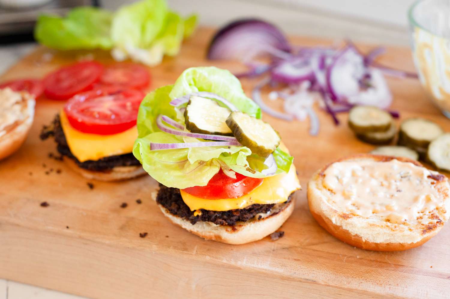 Black Bean Smash Burger Assembled on a Cutting Board (Tomato Slice, Lettuce, Onion Slices, and Pickles Topping the Patty in a Burger Bun)