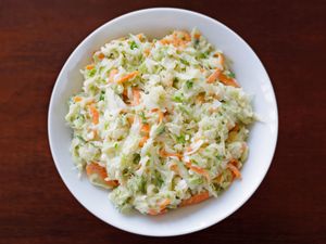 A bowl of coleslaw placed on a wooden surface