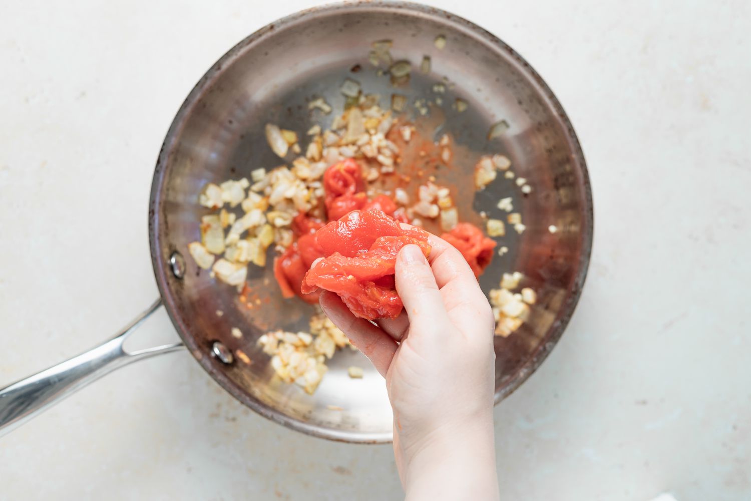 Adding tomato to a skillet to make chile relleno casserole.