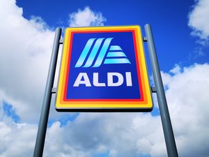 An Aldi logo on a sign in front of a sky with clouds