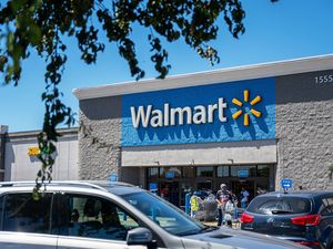 Exterior of a Walmart store with parked cars and some customers near the entrance