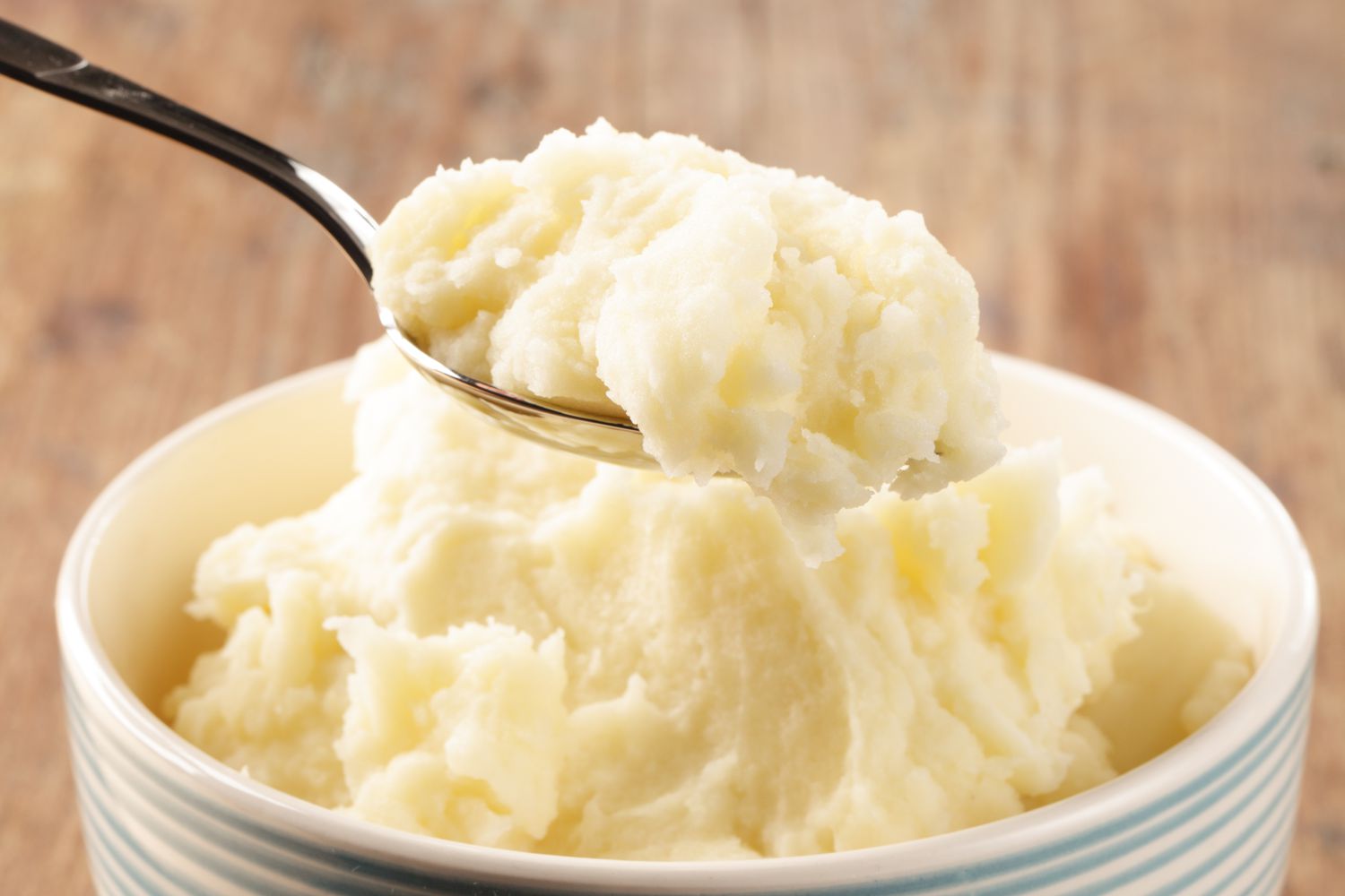 Creamy mashed potatoes in a bowl, getting scooped out with a spoon