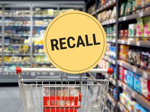Shopping cart in a supermarket aisle with a recall sign displayed