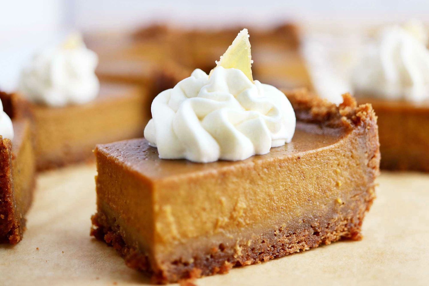 Side view of Pumpkin Pie Bars with Graham Cracker Crust topped with whipped cream.