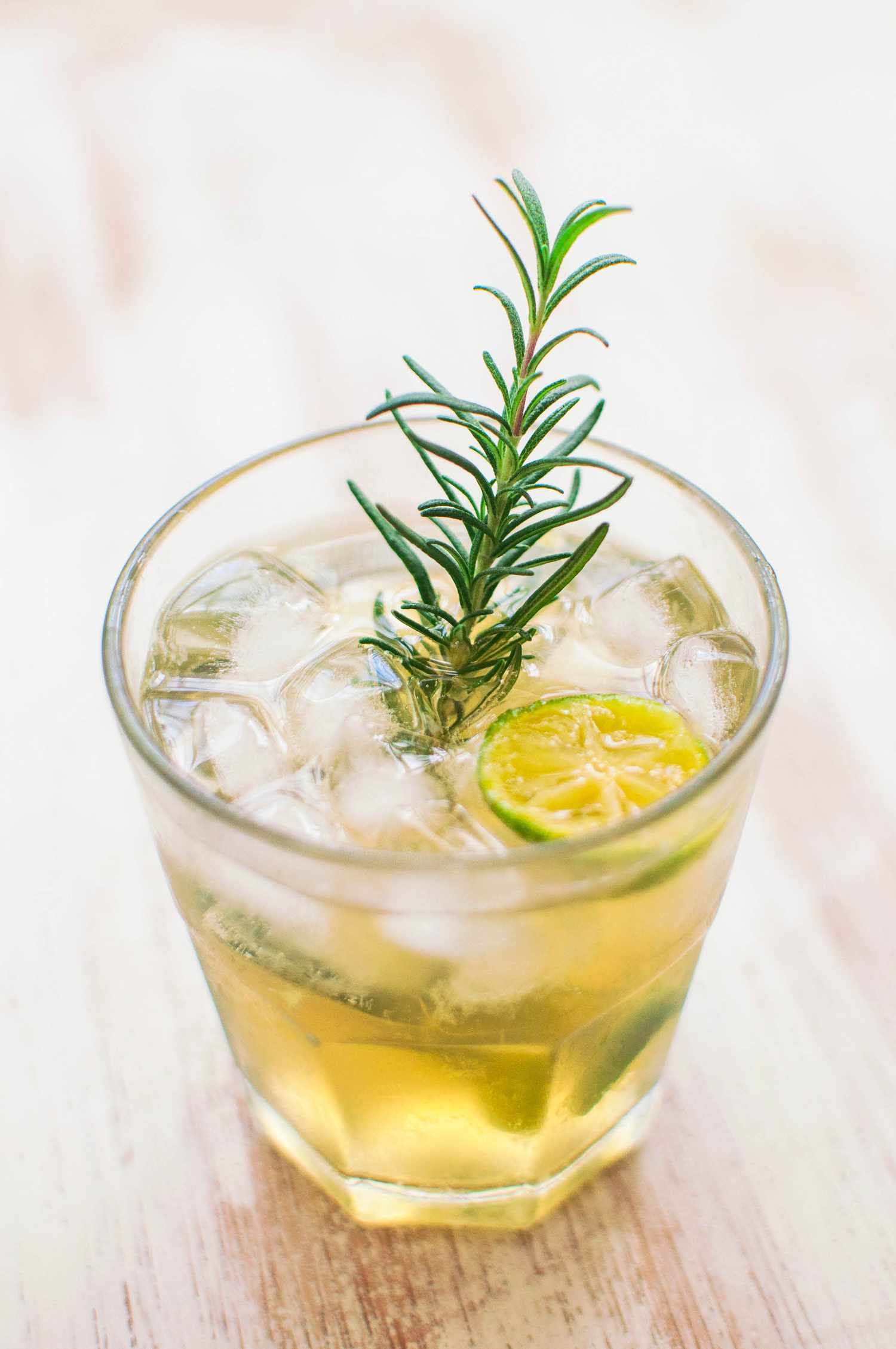 A Calamansi Drink With Ice, a Rosemary Sprig, and a Halved Calamansi