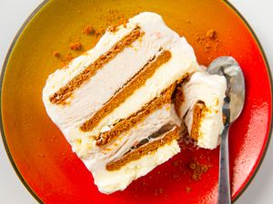 A slice of ice cream cake layered with cookies on a plate with a spoon