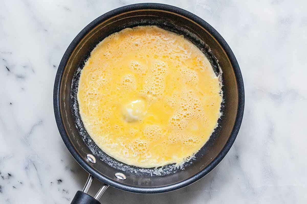 Whisked eggs cooking in a non-stick omelette pan