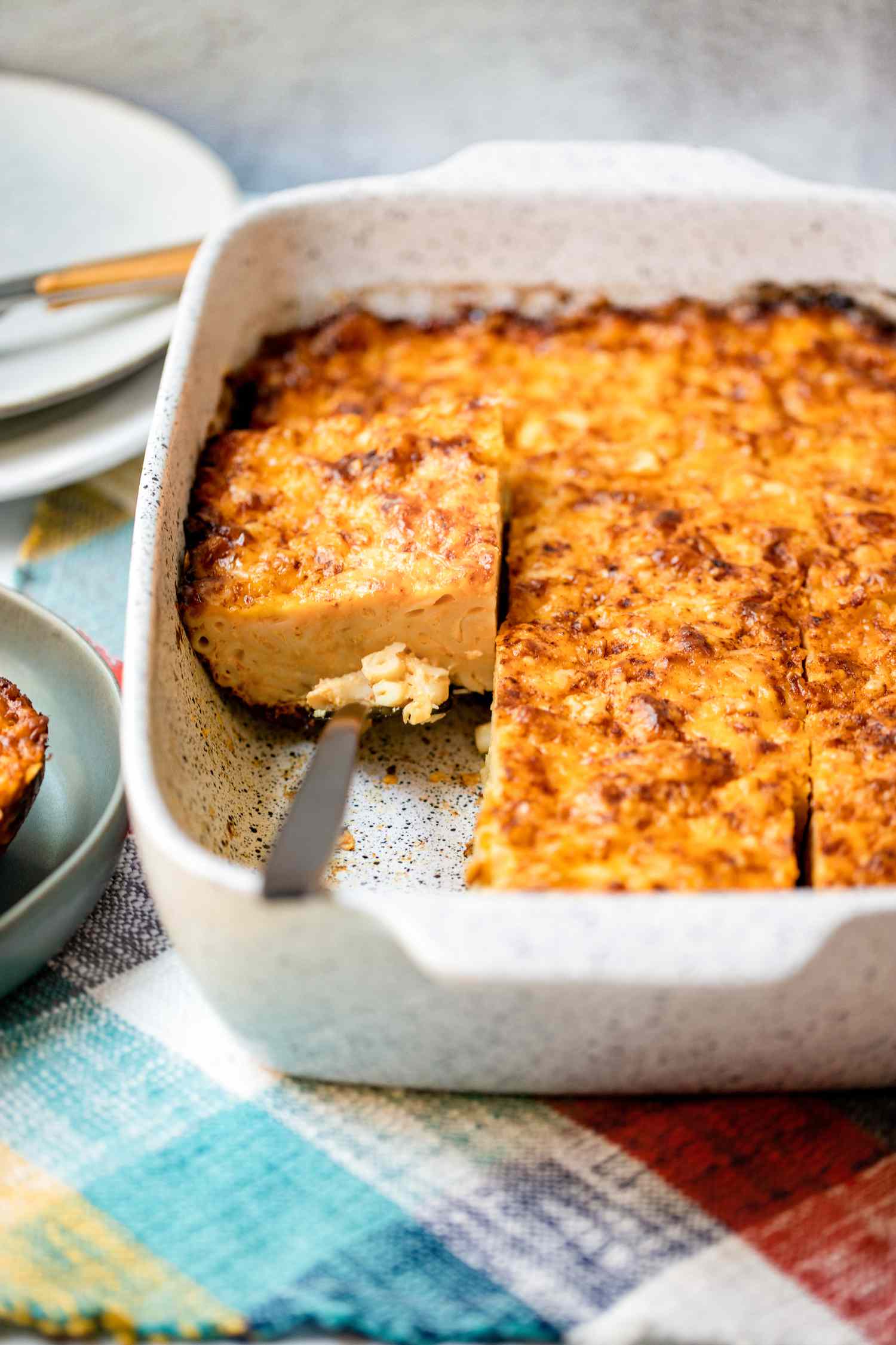 Casserole Dish of Trinidadian Macaroni Pie Cut into Individual Servings with One Piece Lifted Using a Spatula 