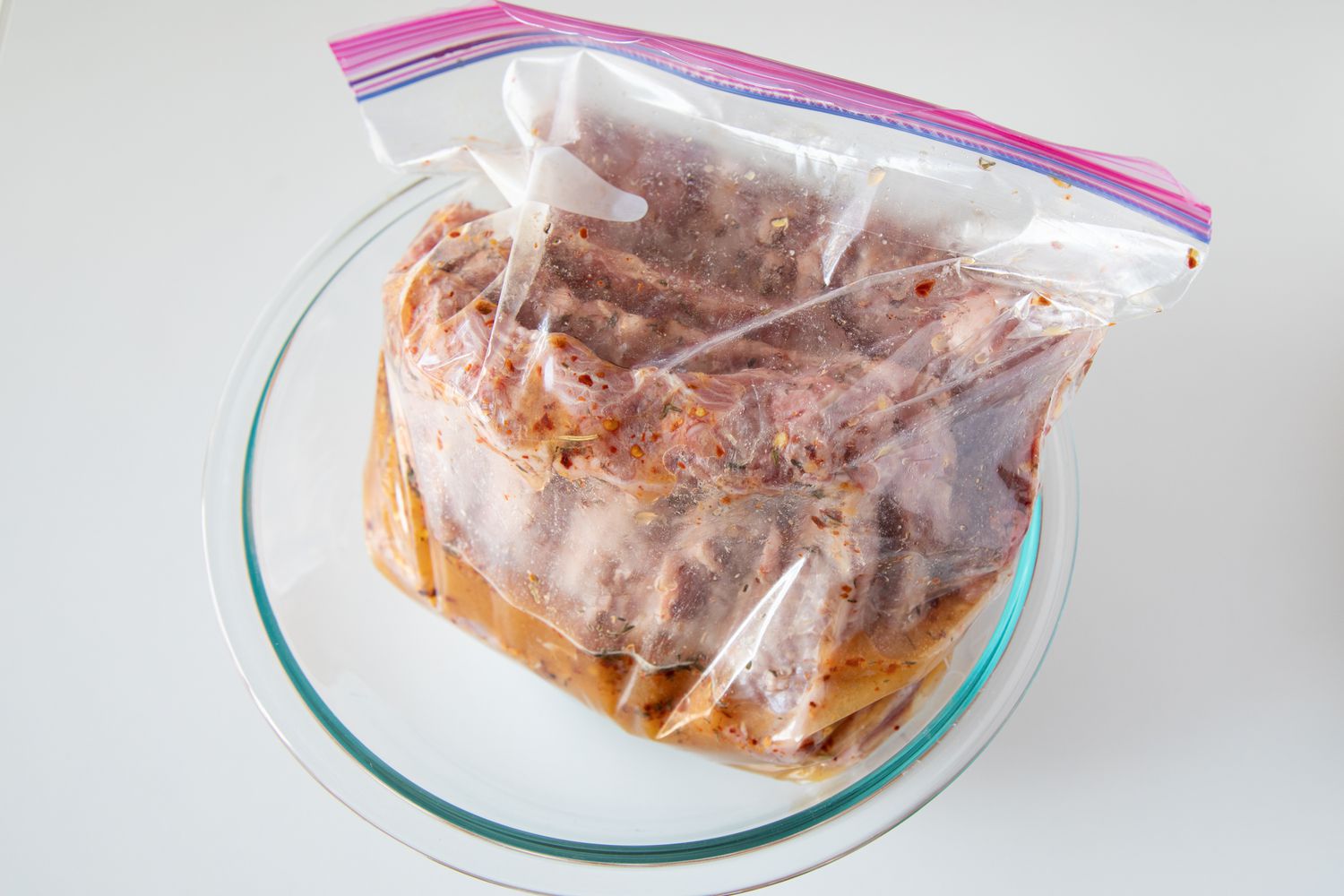 Ziplock bag with brine for ribs inside a glass bowl.