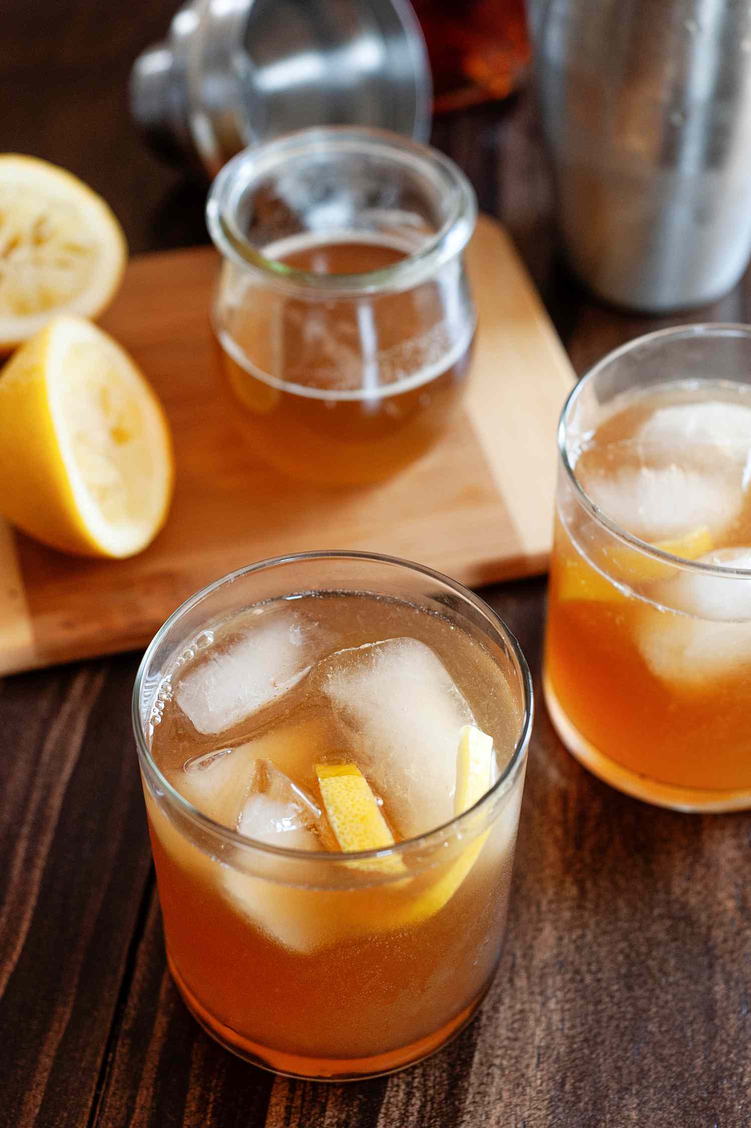 Two Gold rush cocktails with ice on a wood background.