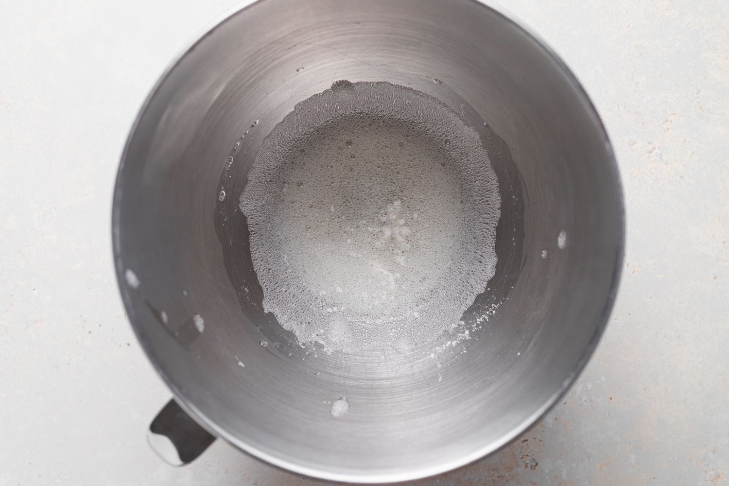 A metal bowl with egg whites inside to make chocolate macaron.