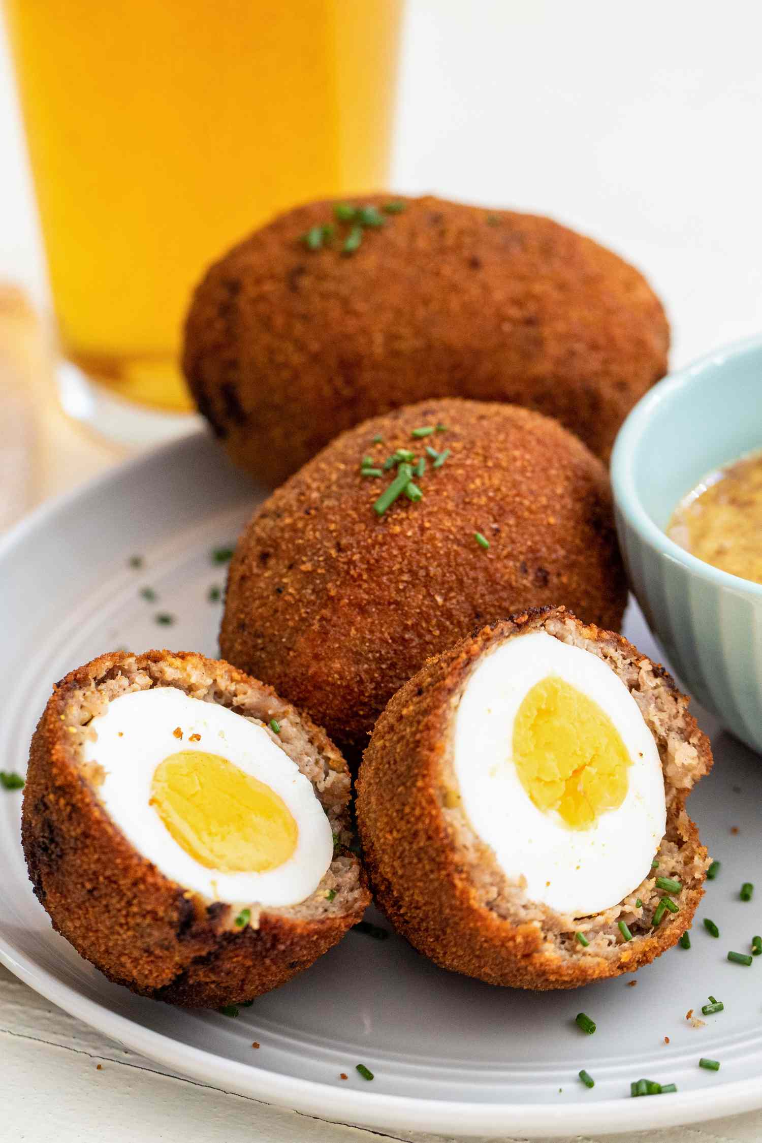 Scotch eggs on plate with a pint of beer.