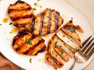 Grilled pork chops served on a plate with garnish and a fork