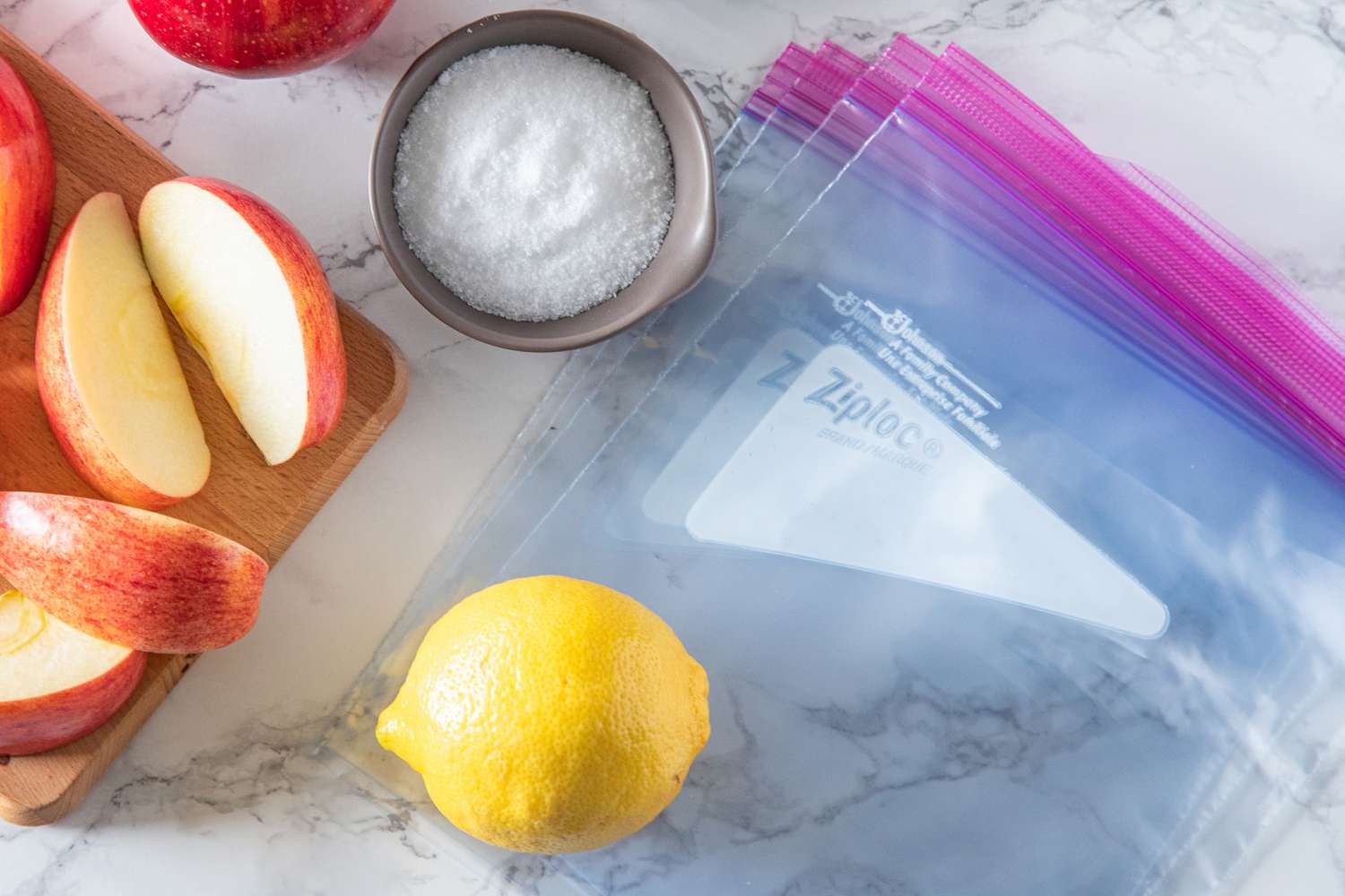 ziploc bagson the counter next to a lemon, bowl of kosher salt, and apple slices