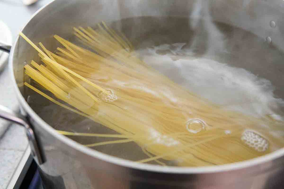 dry spaghetti noodles in pot with water