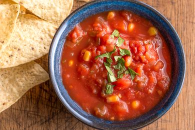 A blue bowl filled with salsa, with tortilla chips on the side
