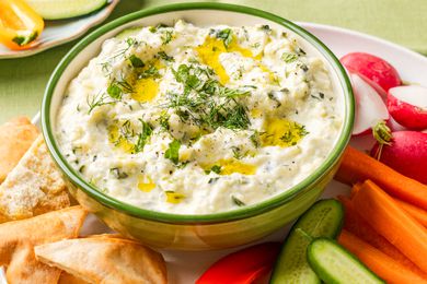 zucchini dip in a bowl on a plate with sliced vegetables