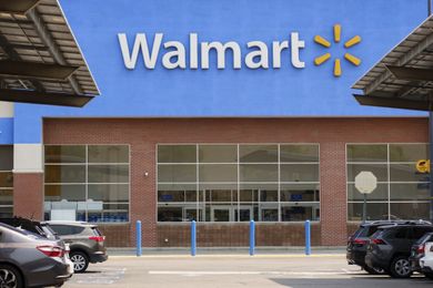 Exterior entrance to a Walmart store with parked cars in the foreground