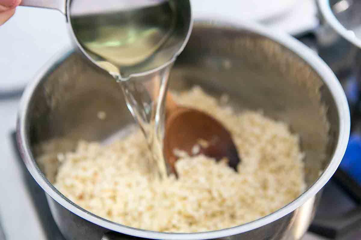 add white wine to summer vegetable risotto in pot