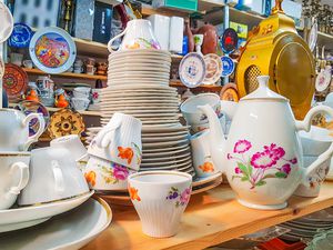 Different used vintage porcelain dishes and other home related objects in flea market second hand shop